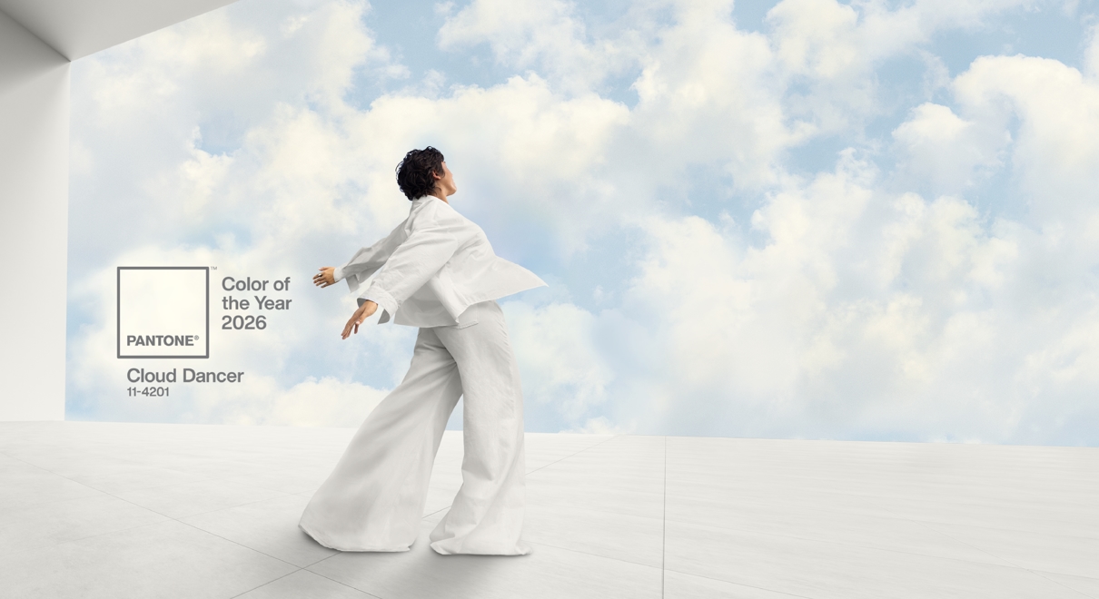 mn in white suit infront of a green screen of the sky with clouds