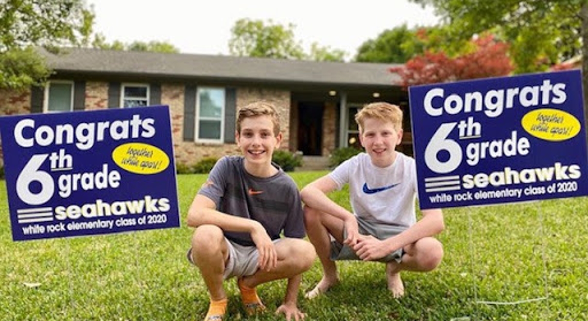 Two Boys posing with their 6th grade graduation signs