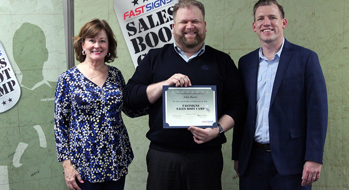john burns receives a certificate for completing the fastsigns sales boot camp