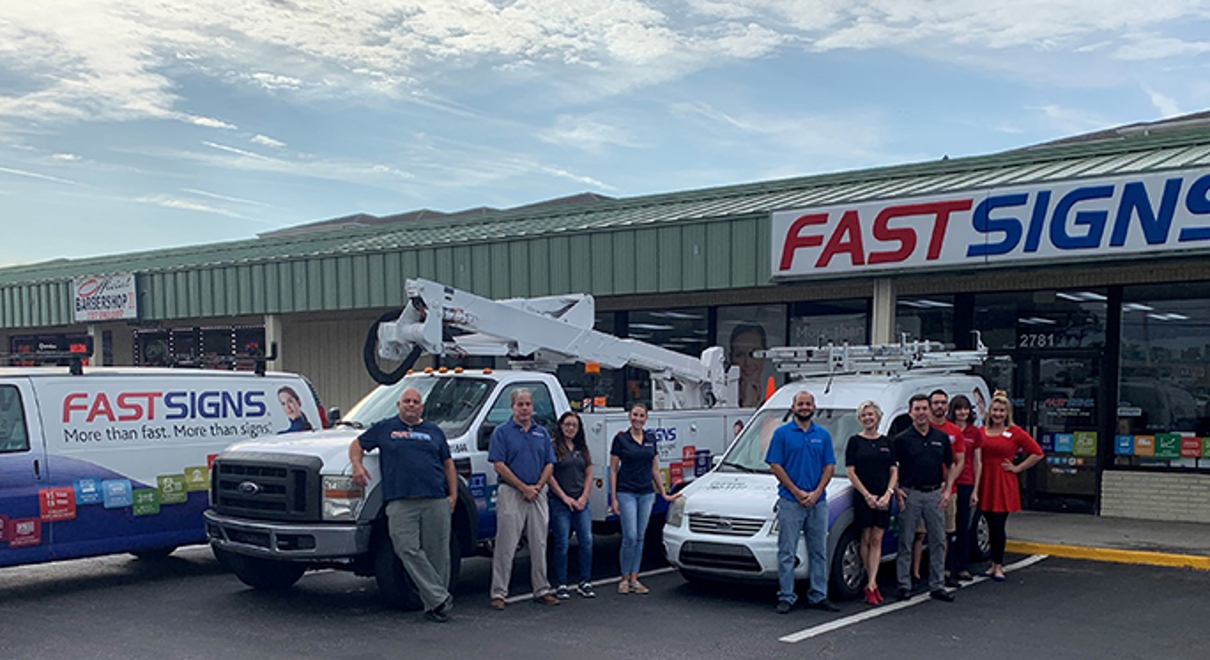 the FASTSIGNS of Largo team stands outside their storefront