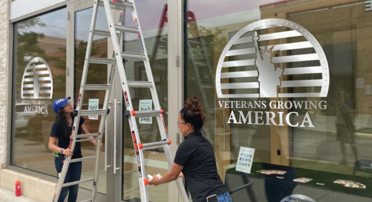 Rawna Elghandour and Sabrina Xaviar, of FastSigns in Stafford County, put up signs for a new Veterans Growing America pop-up store in Woodbridge.