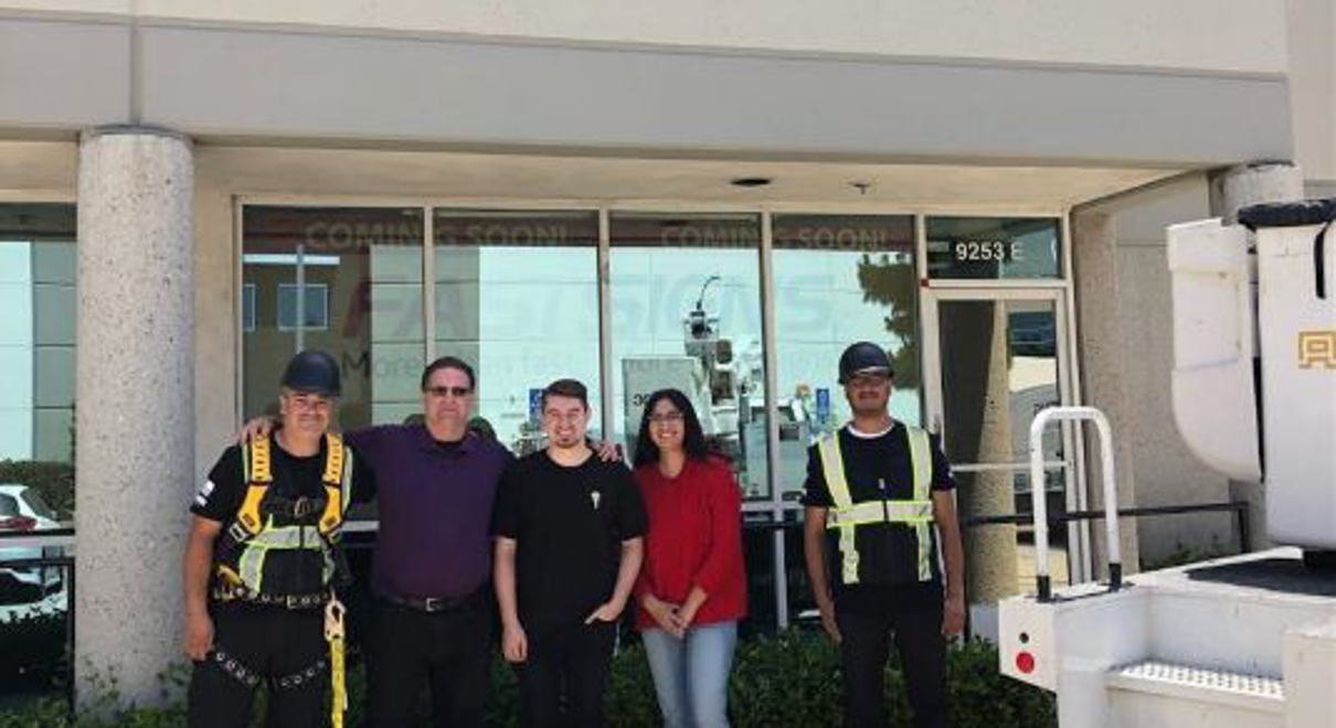 Five people standing in front of Fastsigns building.