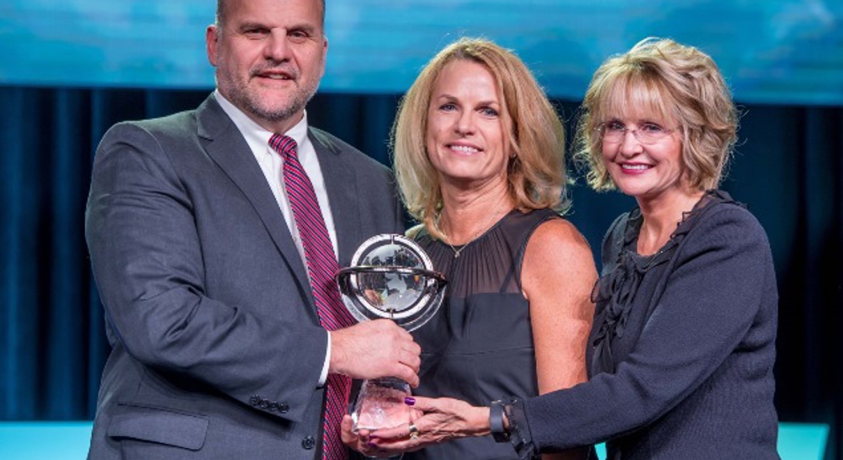 Owners Robb (left) and Stacy Schmit (center) received multiple awards presented by Catherine Monson (right), CEO of FASTSIGNS International, Inc., at the 2018 FASTSIGNS Convention.