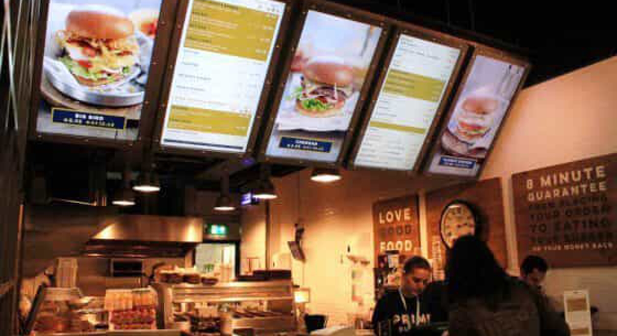 a restaurant uses digital signage over the cashiers