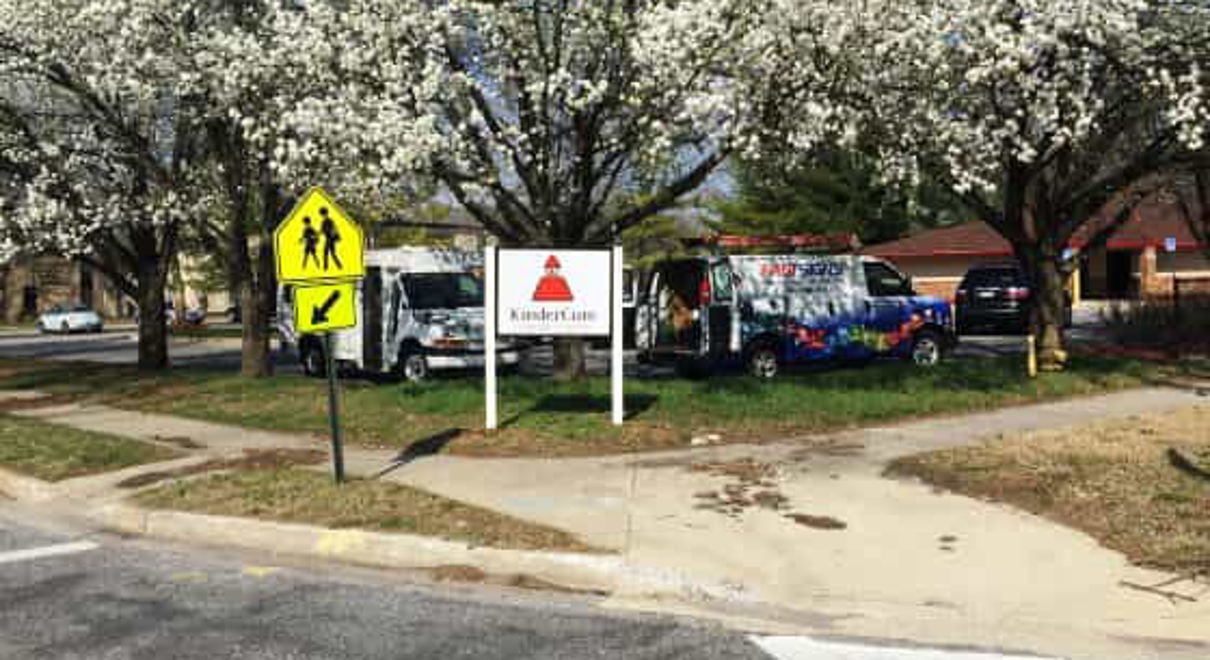A kindercare sign in front of blooming trees