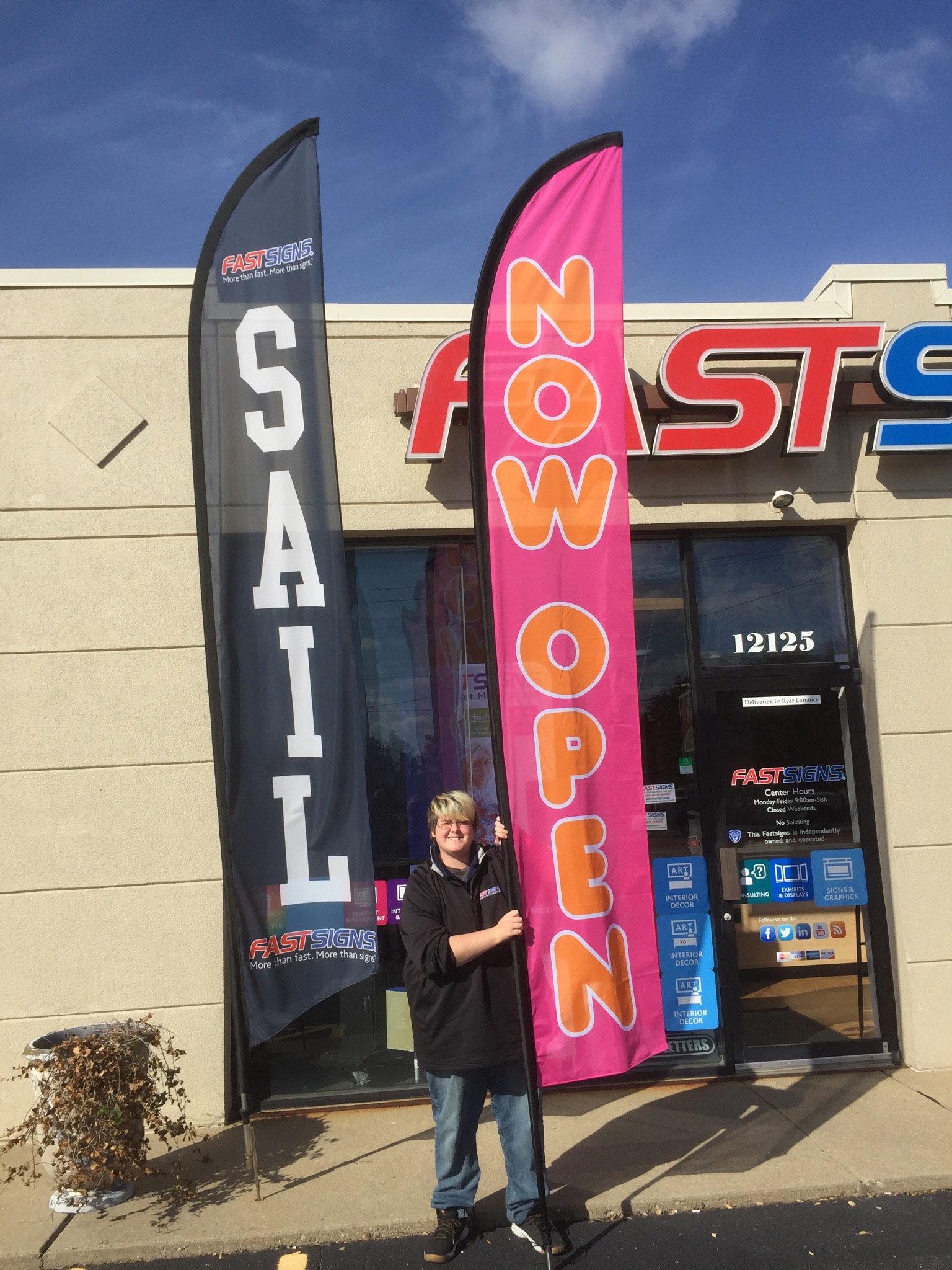 Man holding a feather flag outside the fast sign office