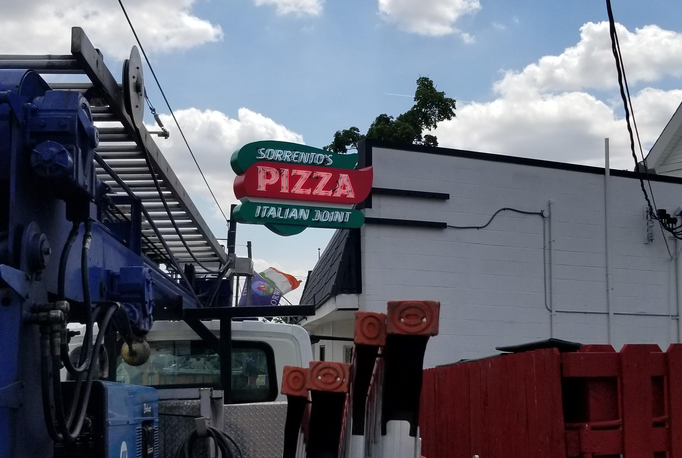 A neon pizza restaurant sign after custom sign installation