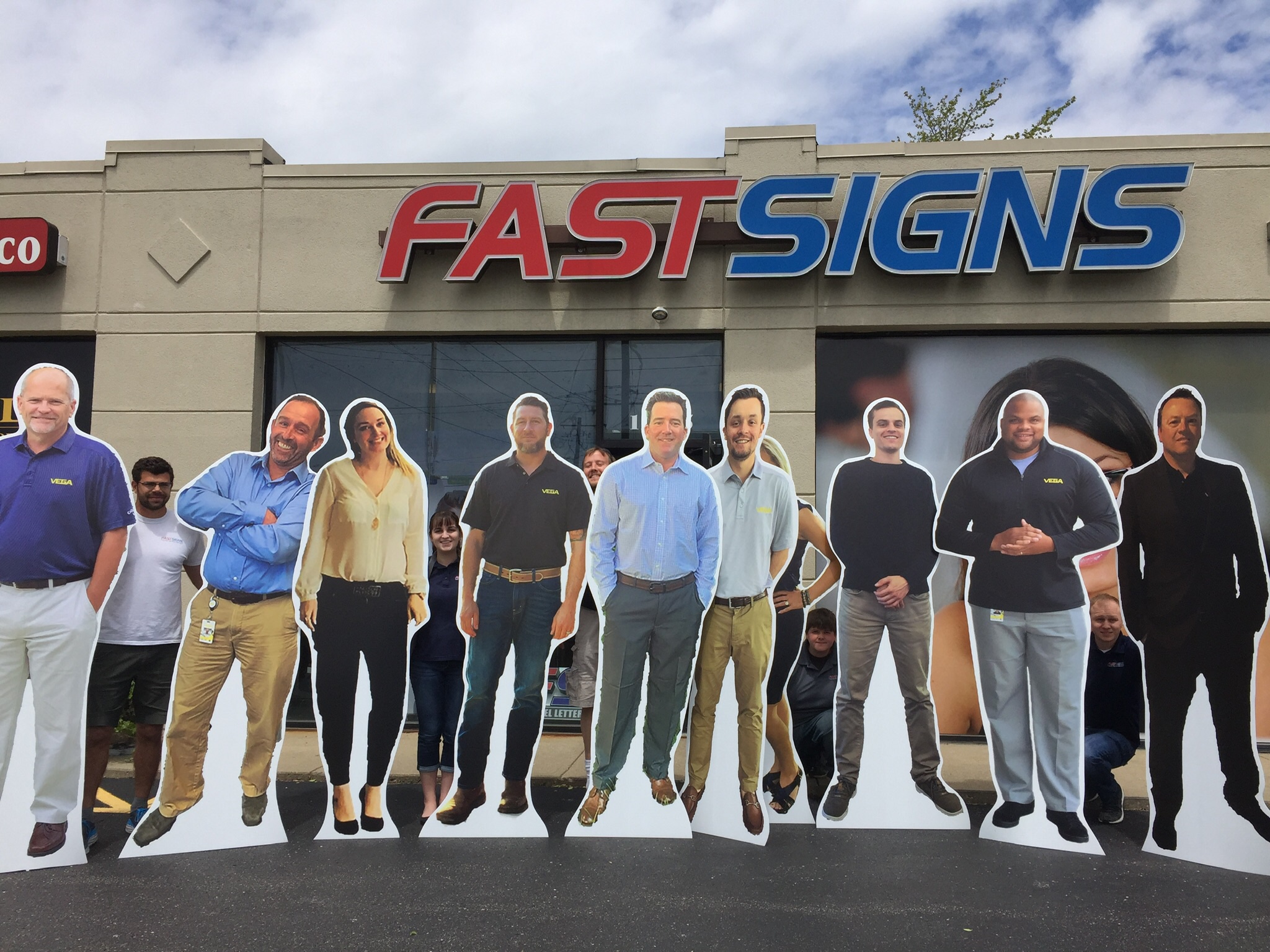 group of people holding the standees on the front of fast sign office
