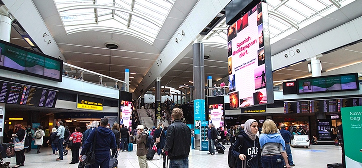 A busy airport with many screens and signs around