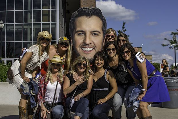A group of fans pose with a large cut out of Luke Bryan's face