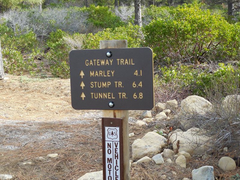A sign on a hiking trail shows the distance to various trails