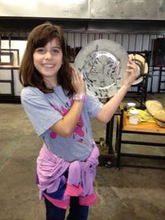 A student stands with a custom plate she made out of recycled material