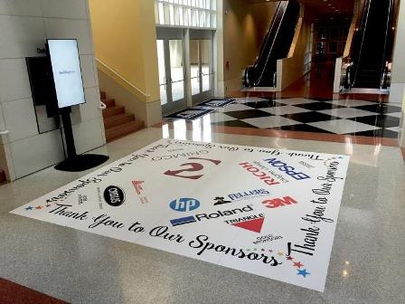 A floor graphic highlights sponsors