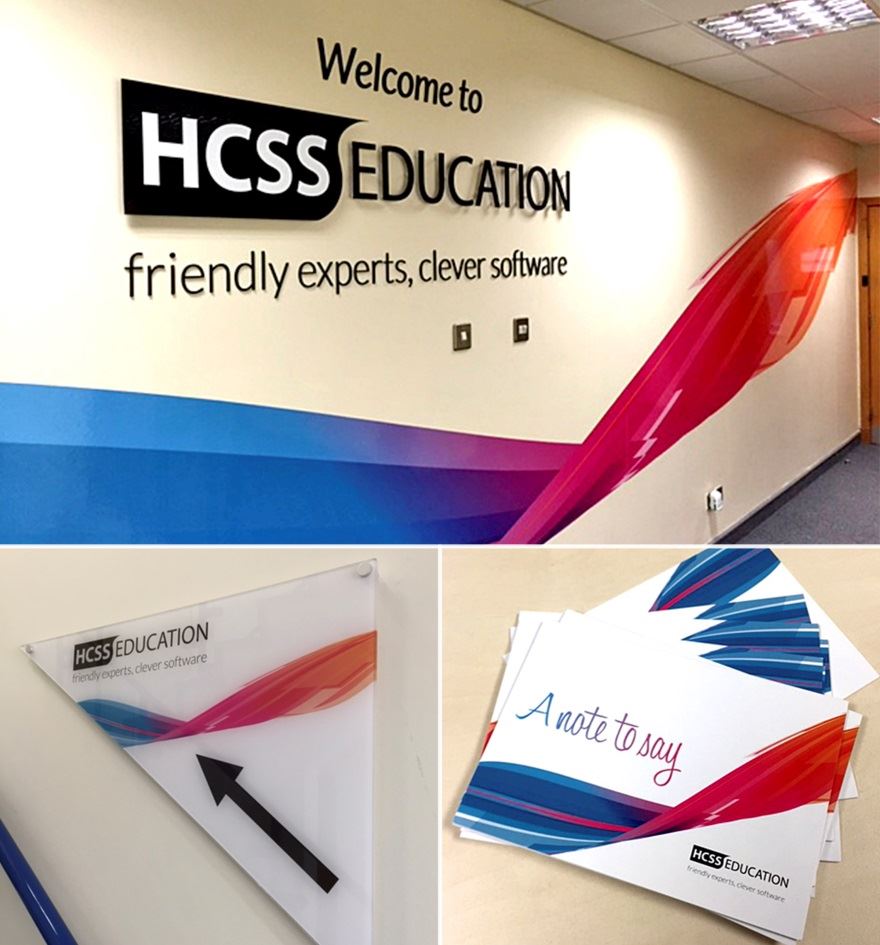 A wall has the HCSS logo on it, with a wall sign and stationary with their logo