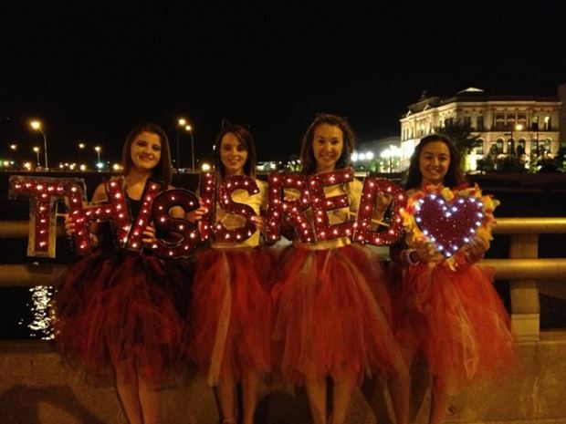 Taylor Swift fans hold custom illuminated letters that spell out "This is Red"