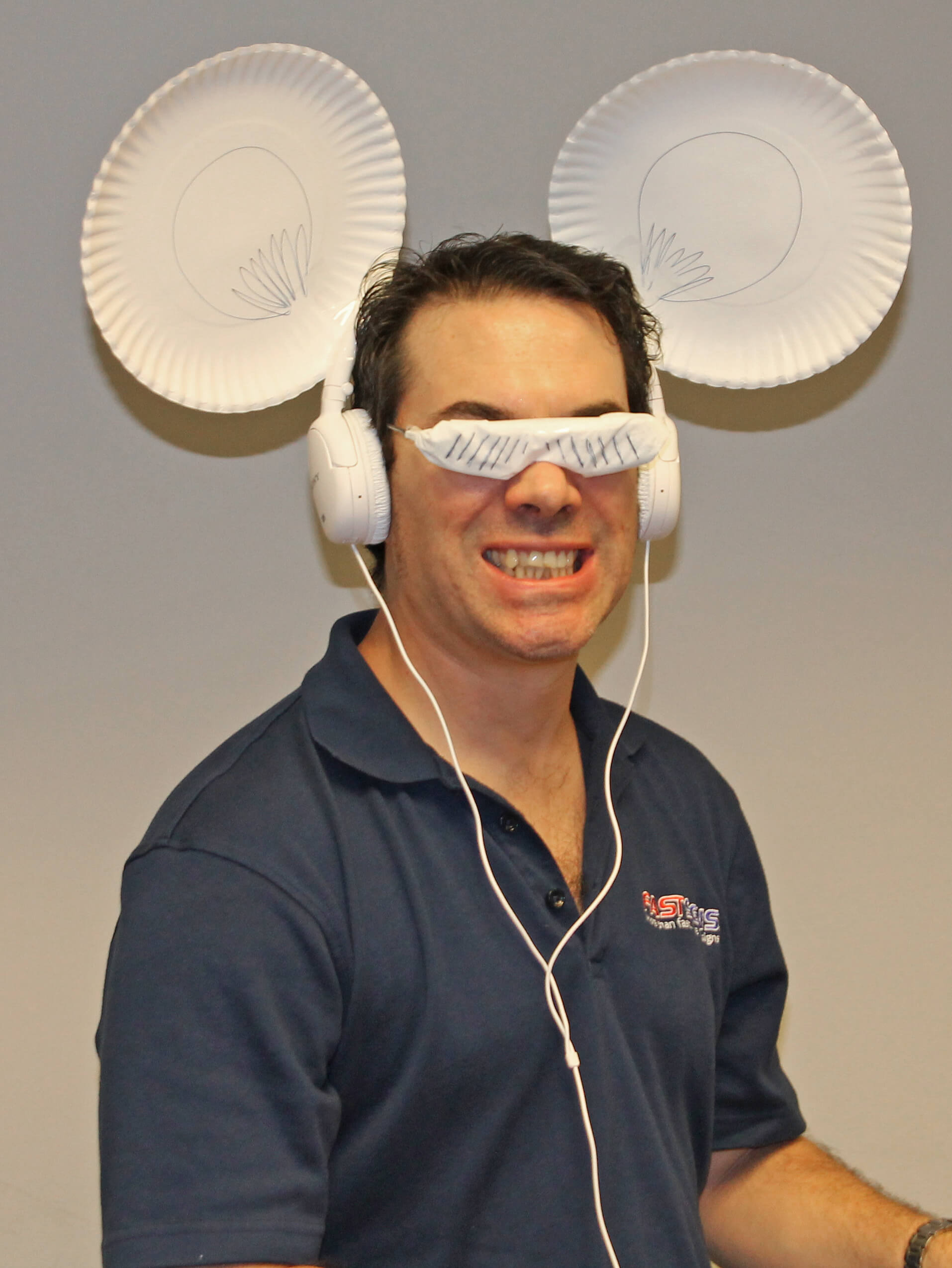 man smiling wearing headphones attached with paper plates and sunglasses 