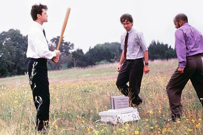 A screenshot from the movie Office Space where the characters destroy a fax machine