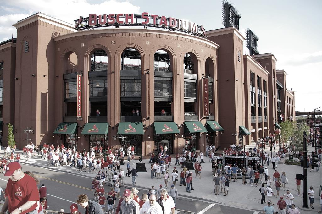 An old photograph of Busch Stadium with fans walking outside of it