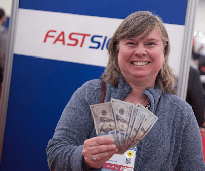 A woman smiles while holding a cash prize she won
