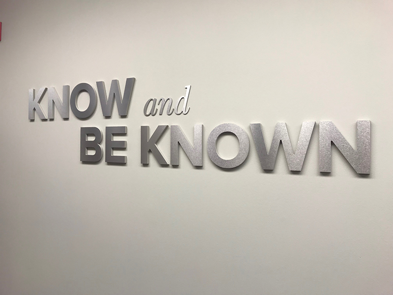 A metal wall sign with lettering that reads “Know and Be Known,” installed by FASTSIGNS in an office building in Burien, Washington