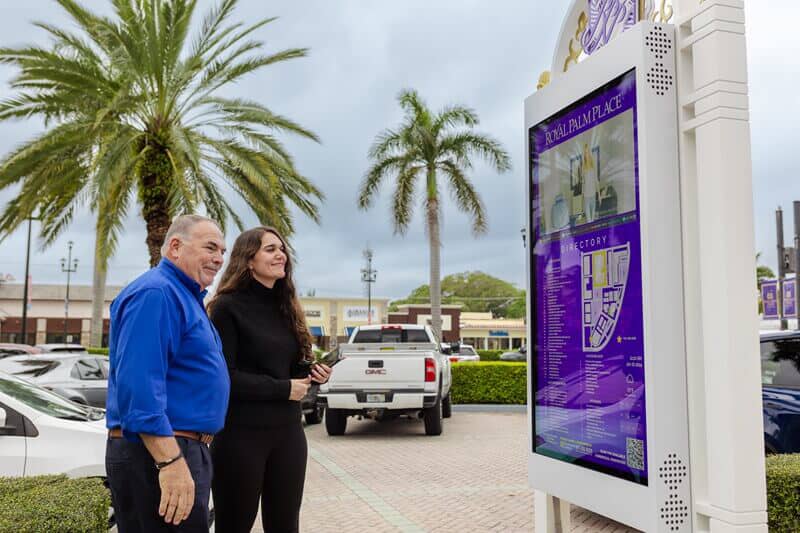 An image of two people looking at a directional/wayfinding map outside.