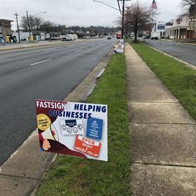 A yard sign is placed on the side of the road