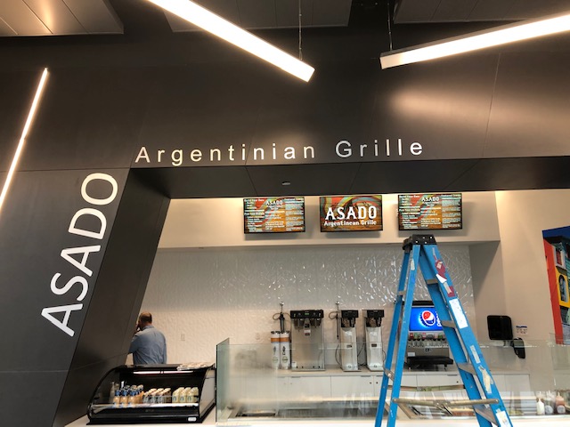 Asado grille menu on the store with ladder on the front and employee working