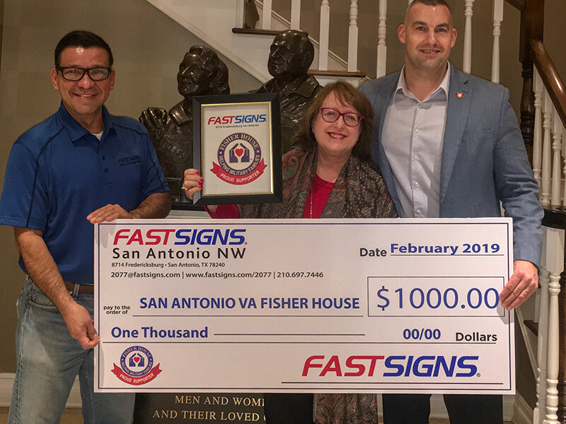 FASTSIGNS San Antonio workers holding donation check for $1,000