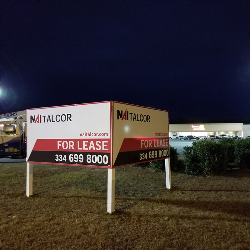 NAI TaLcor For Lease signage on an empty lot with white building as a background
