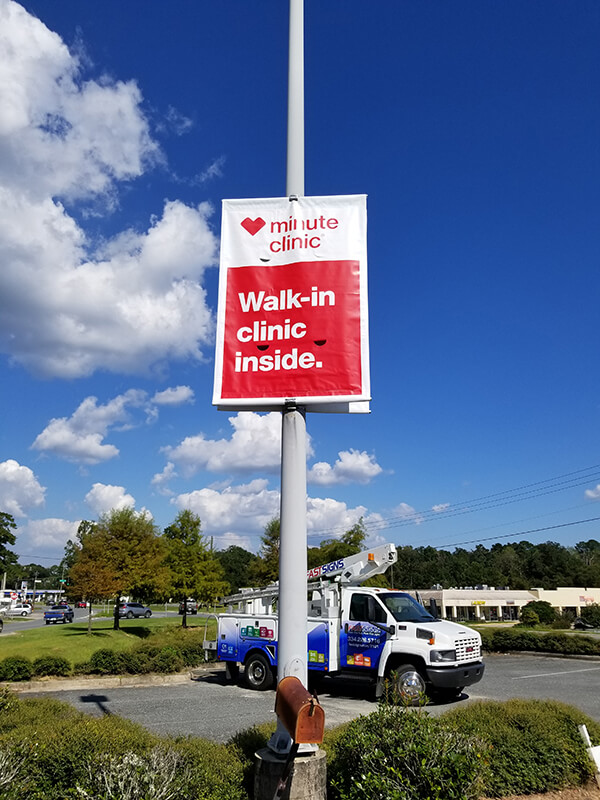 Minute Clinic banner on the pole along the stree with blue tow truck on the back 