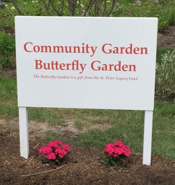 White and red community garden signage with flower and plants