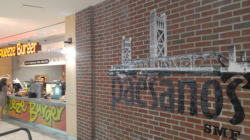 Paesanos sign on the brick wall with a store by the side