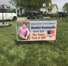 Custom banner for graduate student place on the side of parking space with cars and building at the back