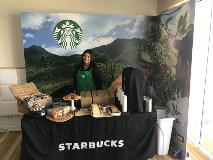 Starbucks banner and products with a Starbucks employee