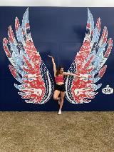 girl posing in colorful wings drawing with blue background and brown floor