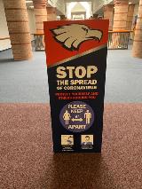 Signage in the middle of a public place with COVID awareness message with graphics