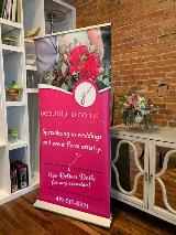 Pink signage standee with image display with white shelf and glass table