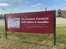 Red banner for Helzberg diamond standing on the ground with buildings in the background