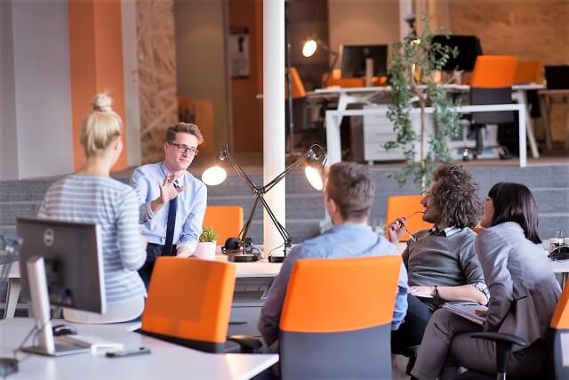 a group of employees speak to one another in an office