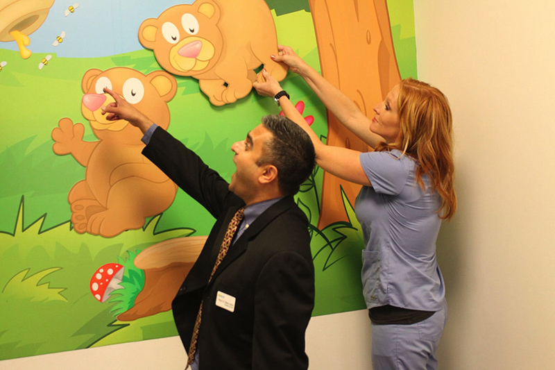 two employees play with images on a wall of cartoon bears