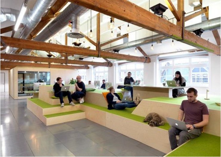 many employees and a dog sit on a modular sitting area
