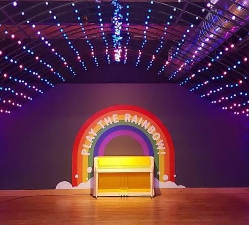 Rainbow graphics on the stage with lights and piano
