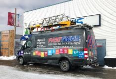 Van wrapped with fast sign graphics parked outside the building