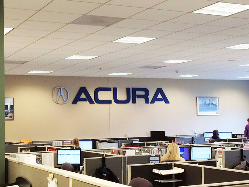 Accura logo on the wall of the office with employees working