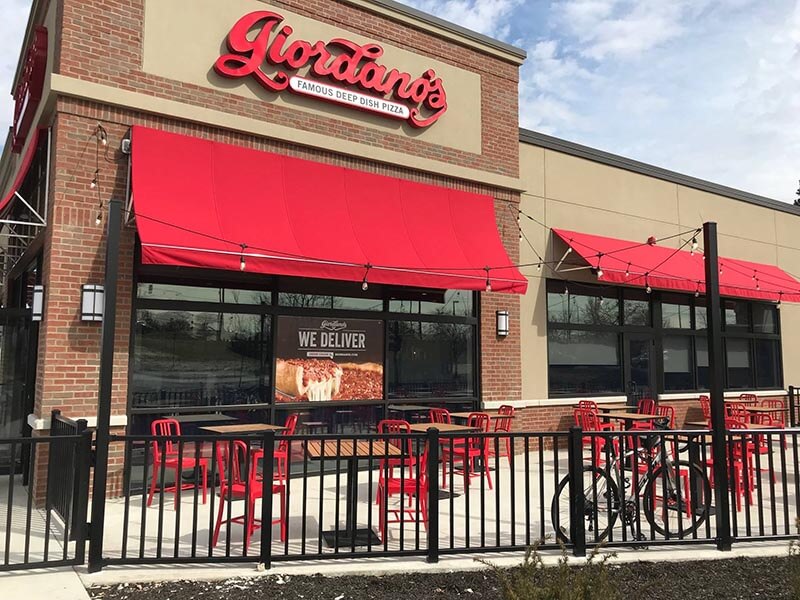 Giordano's Restaurant Logo on the restaurant store with chair, bike and fairy light  outside
