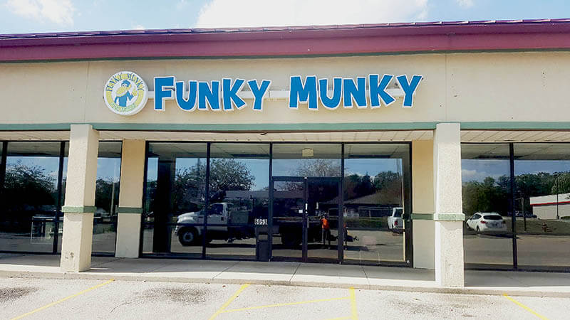 Funky Munky custom sign on the store with cars parked on the side