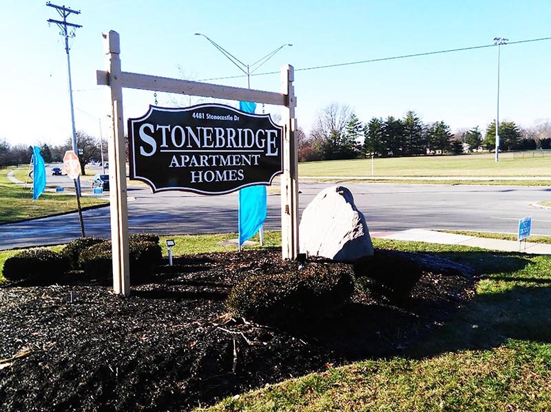 Stonebridge Apartment signage on the side of the road with rocks and plants by the side