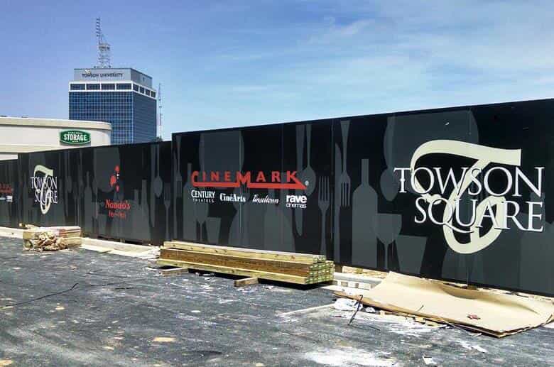 Logos are printed on a construction site wall