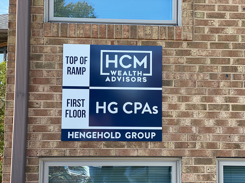 HCM Wealth Advisors sign on the brick wall with window on top and bottom