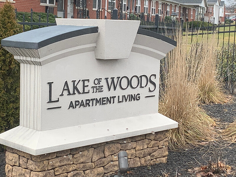 Lake woods apartment signage on the white statue with grass on the side
